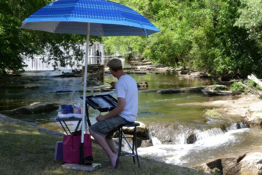 Member of Cedarburg Artists' Guild painting outside near river