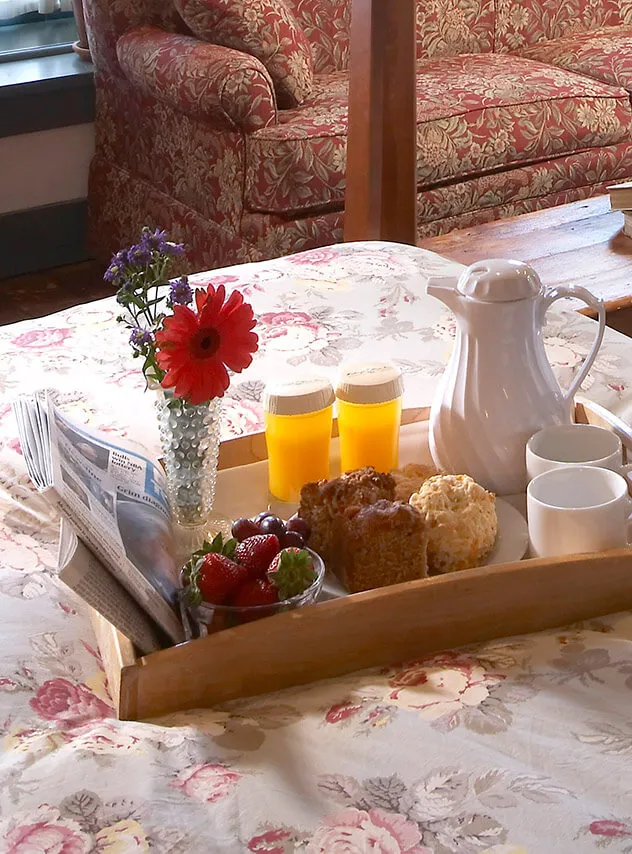 breakfast tray with muffins and fruit sitting on bed