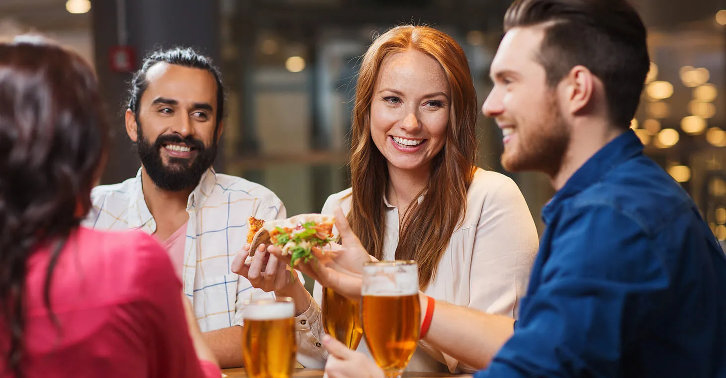 Friends eating pizza and drinking beer together