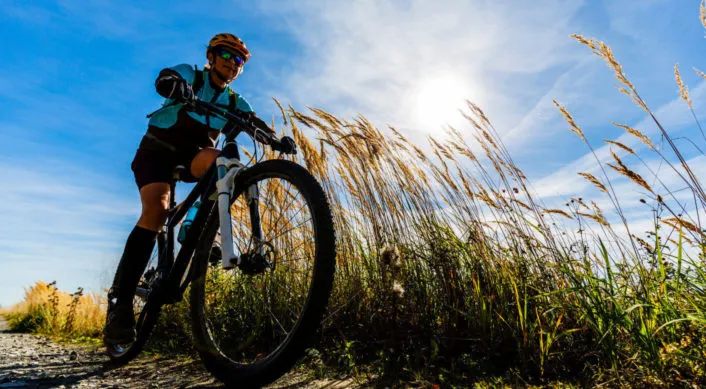 a man biking through wheat with the sun in the background