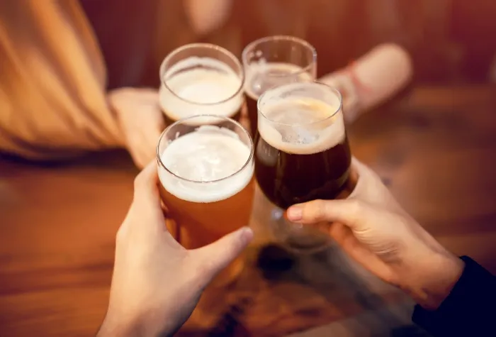 four people cheering with beers