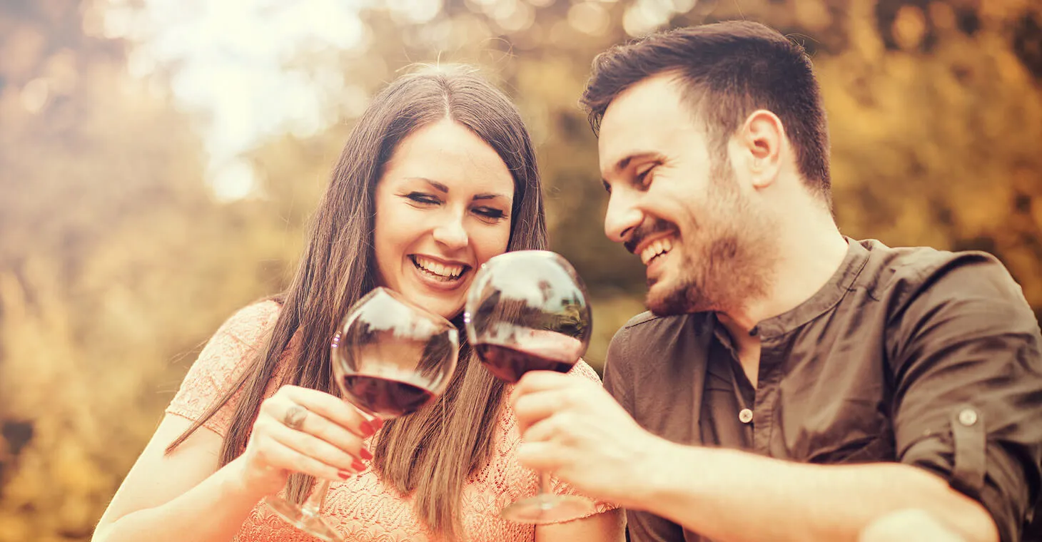 a man and woman laughing and drinking red wine