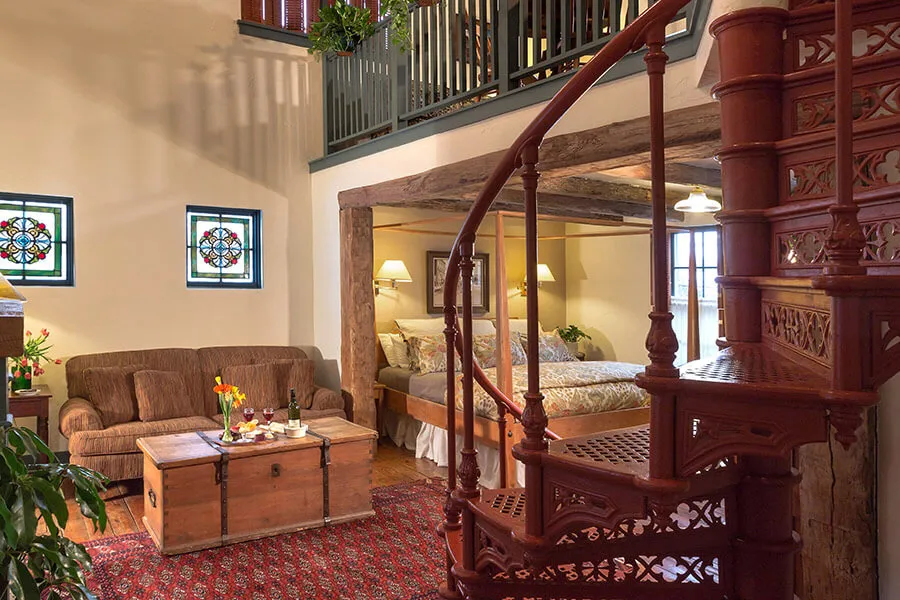 Circle staircase in the foreground, with couch, coffee table and view of upstairs loft area