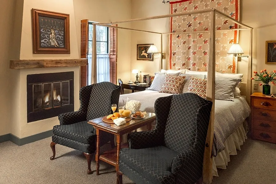 Historic hotel room with bed, chairs and fireplace