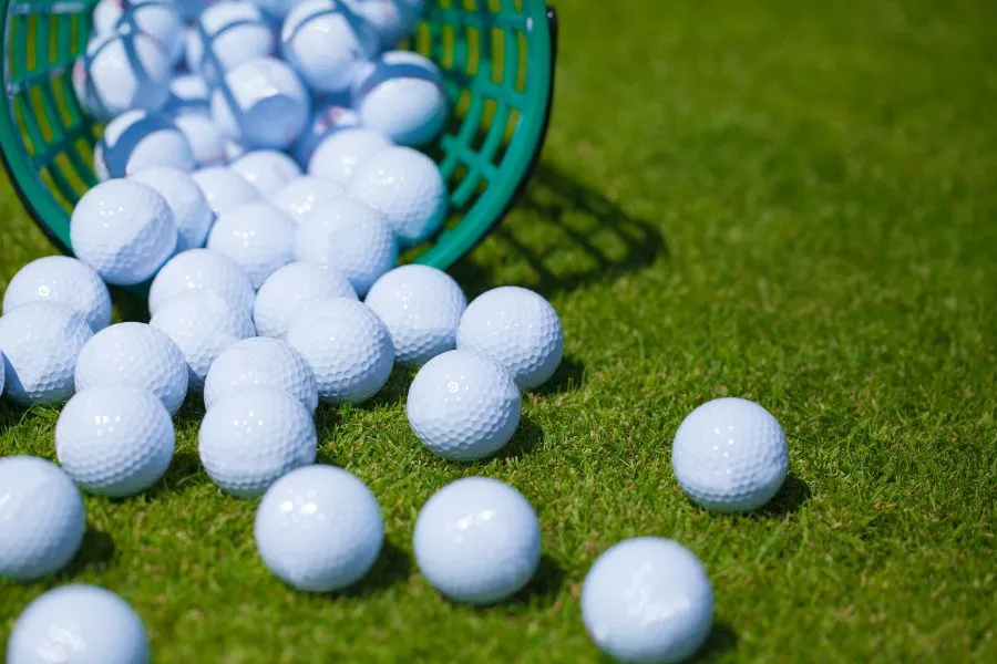 basket of golf balls on grass
