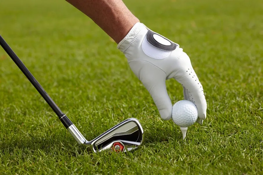 man teeing up golf ball with putter