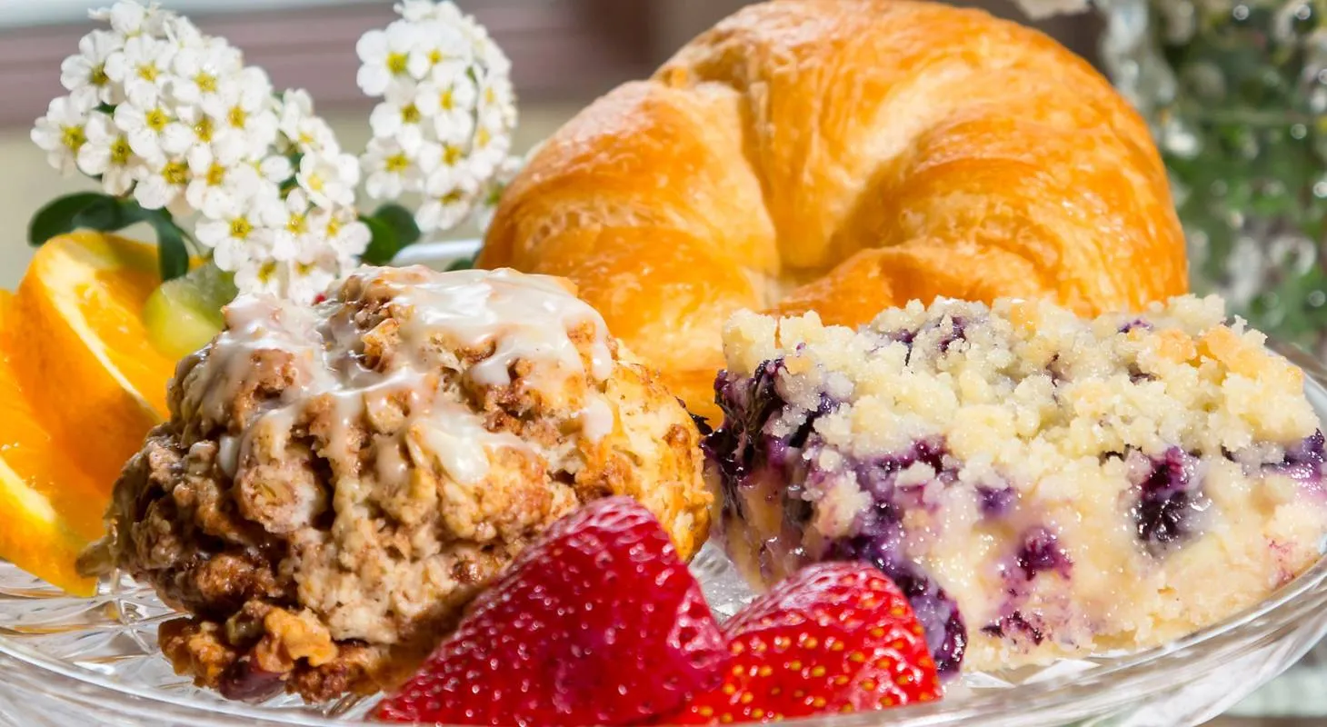 Assorted baked goods, fruit, and flowers on a glass tray