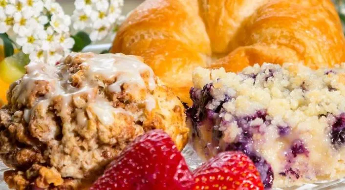 Baked goods, fruit, and flowers on a glass tray