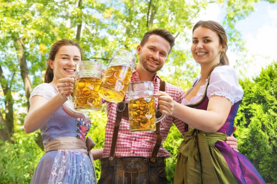Man in Lederhosen and women in Dindl holding beer