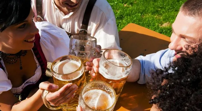Group of friends drinking beer in traditional German clothes at Oktoberfest