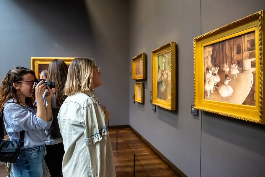People looking at art on the wall of a museum.