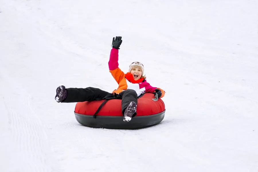 Young girl smiling while snow tubing